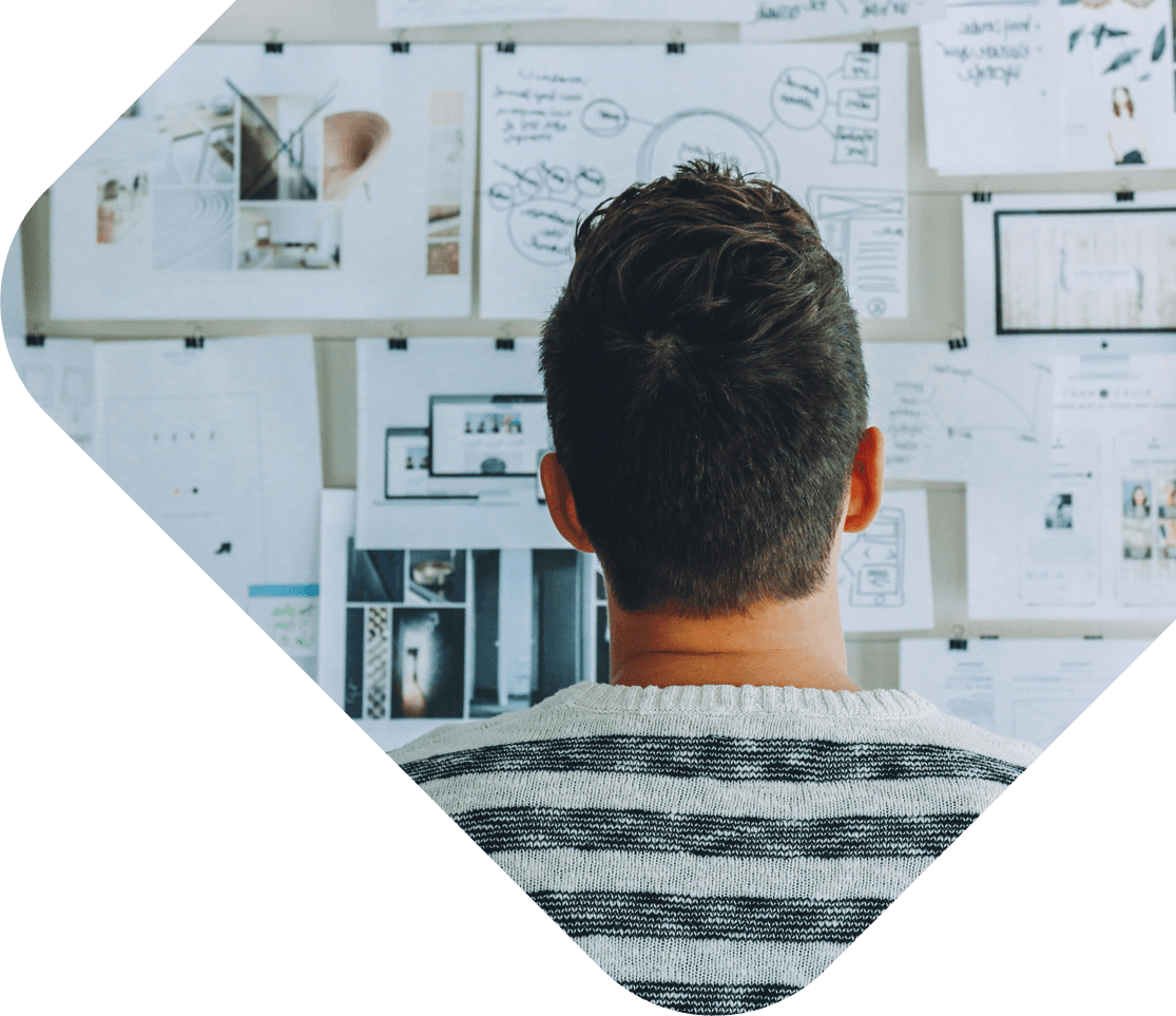 a man looking at a wall of papers and drawings