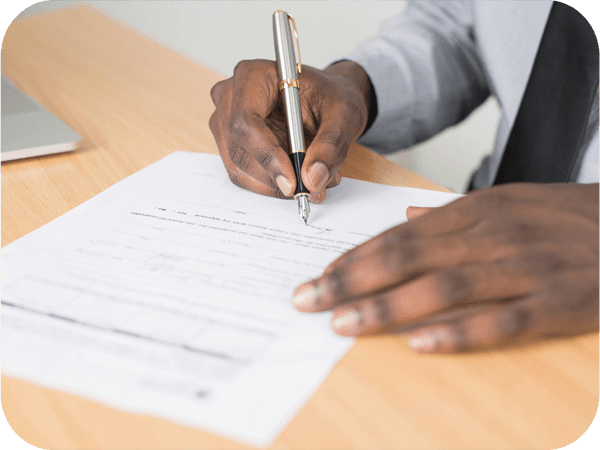 a close up of a man signing a paper